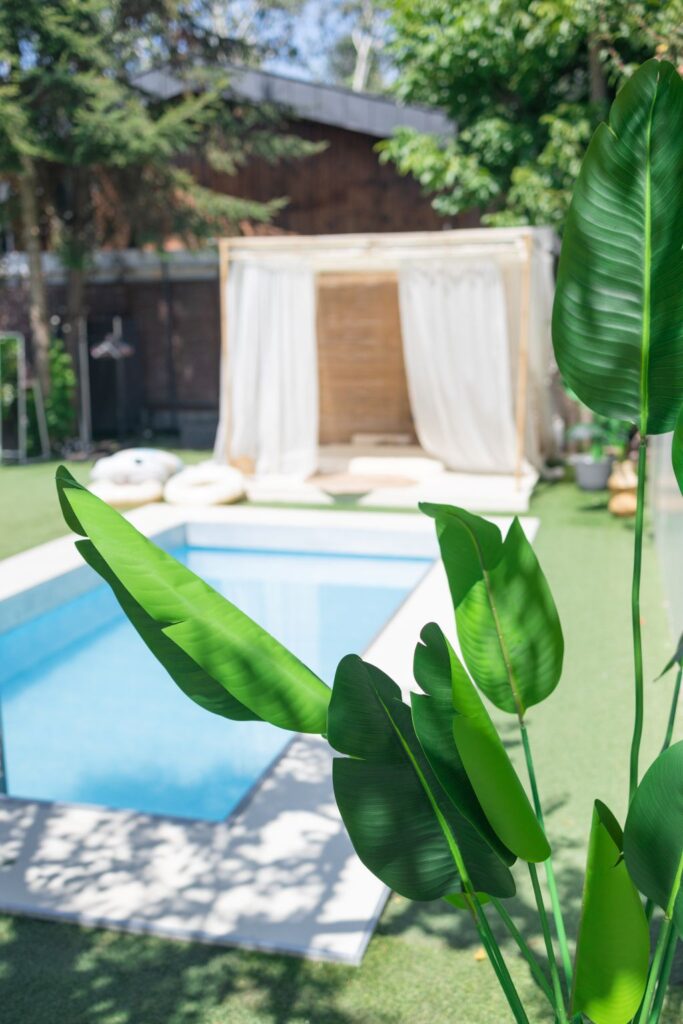 Jardín con piscina y hojas verdes tropicales