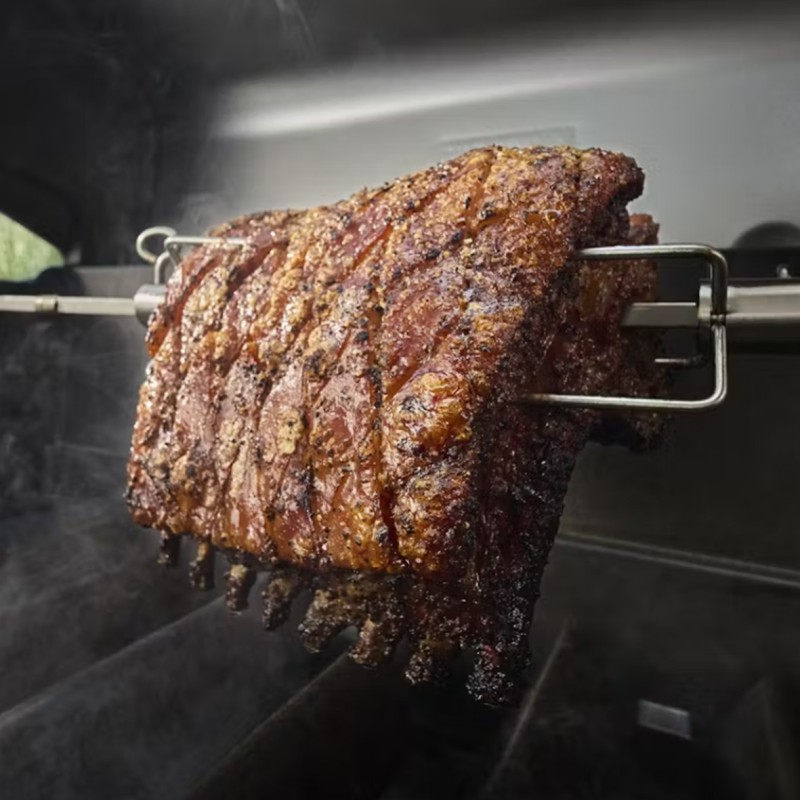 Costillas asadas a la parrilla sobre brasas humeantes.