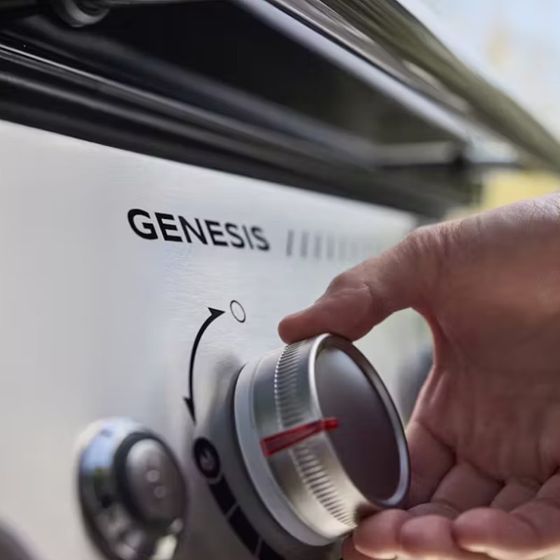 Mano ajustando perilla de una barbacoa Genesis.