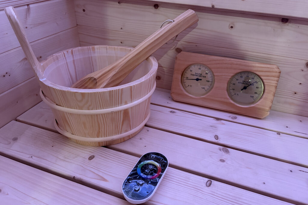 Cubo y termómetro en sauna de madera