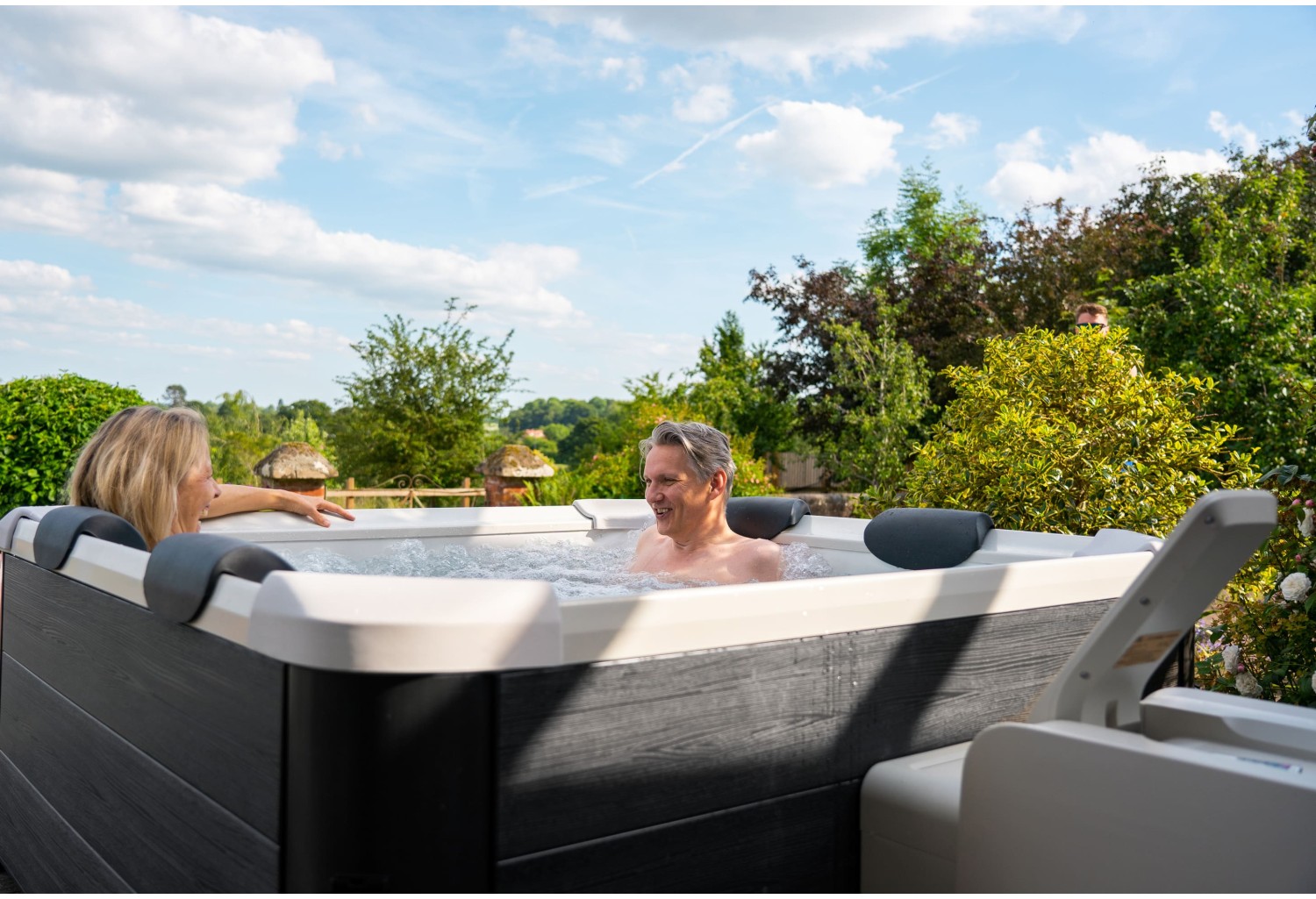 Pareja relajándose en jacuzzi exterior en jardín