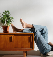 Persona con piernas sobre mueble de madera